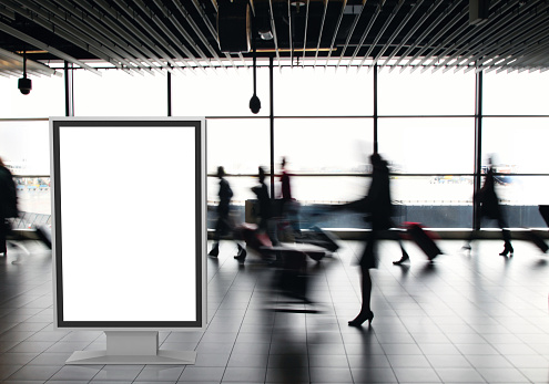 Airport passengers crowd walking blurred people billboard advertisement