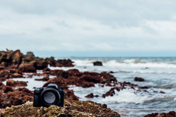 istock DSLR camera on stone beach wet from water sea wave 1090357424