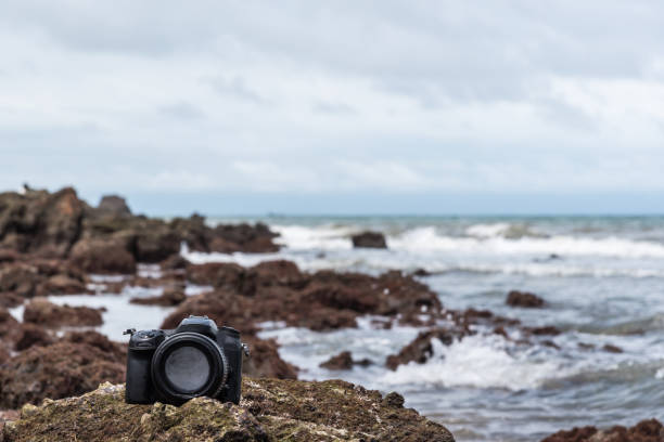 istock DSLR camera on stone beach wet from water sea wave 1090357446