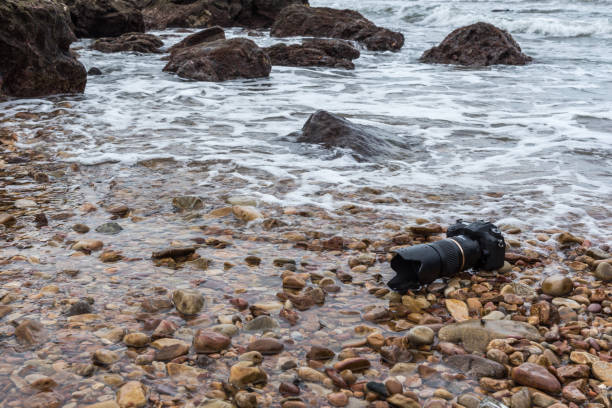 istock DSLR camera on stone beach wet from water sea wave 1090359656