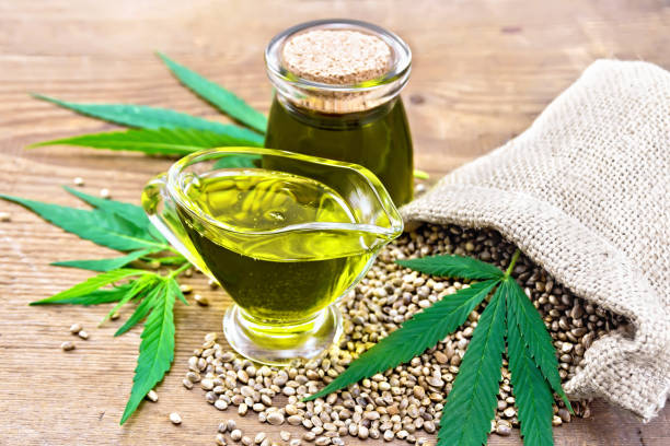 istock Oil hemp in sauceboat and jar on old board 1090370106