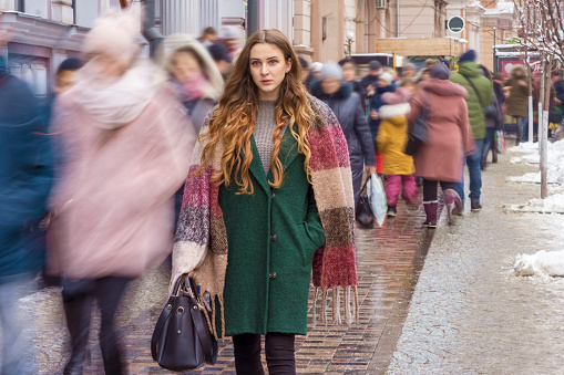 focused woman among moving blurred crowd in winter
