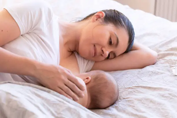 Photo of Close-up of mother breastfeeding and hugging newborn baby. Mom breast feeding her infant baby. Lactation newborn concept. Baby eating milk before sleeping. Mother feed her month son with breast milk