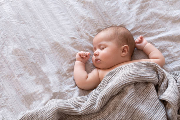 bebé tranquilo acostado en una cama y dormir en casa - newborn fotografías e imágenes de stock