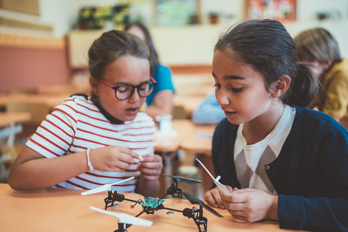 School children in class assembling a drone