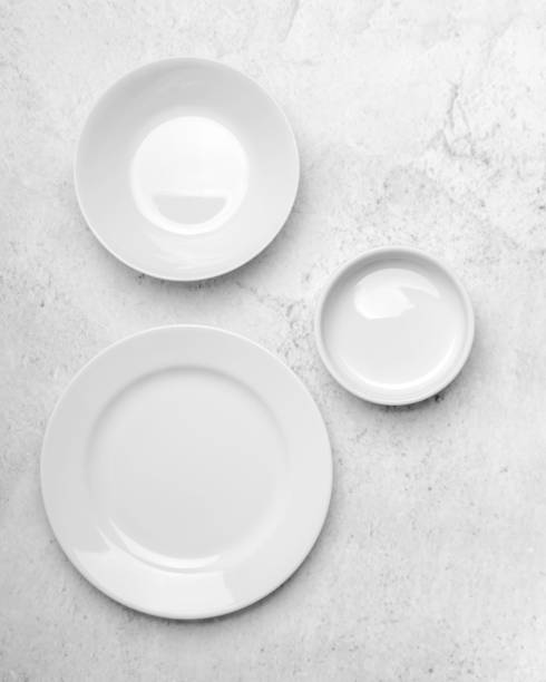 A clean little white plates on light stone background. Minimalistic kitchen, dishes. Top view, flat lay