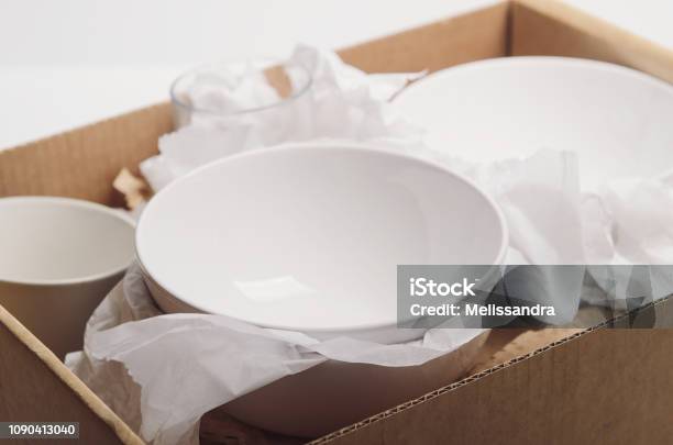 Clean White Dishes In Paper Packed In A Cardboard Box Concept Relocation Stock Photo - Download Image Now