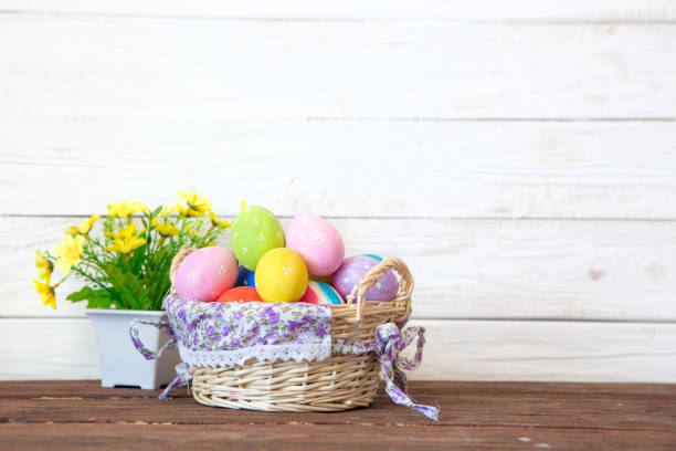 istock Easter eggs in the basket with yellow flowers on brown table on white rustic wooden background 1090418718