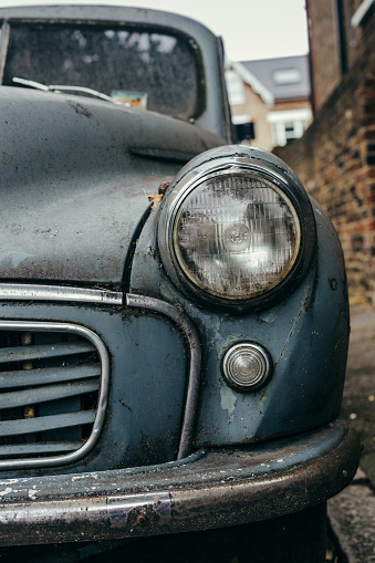 London, UK - July 30, 2018: Close up front view of a headlamp, turn signal and a bumper of an old retro car: