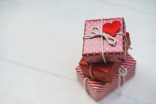 istock Elegant red gift boxes stack decorated with mini heart figure on white wood background, valentine love present concept, copy space 1090426504