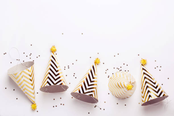 полосатые золотые конусы шляпы и конфетти на белом фоне. концепция праздника рождения - hat conical стоковые фото и изображения