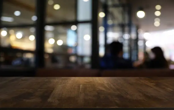 Photo of Empty dark wooden table in front of abstract blurred bokeh background of restaurant . can be used for display or montage your products.Mock up for space.