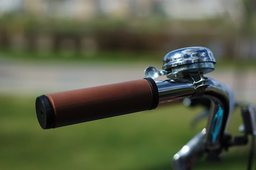 Part of the steering wheel of a vintage bicycle with a bell close up.
