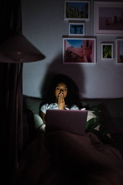 istock Woman in pajamas with a computer yawning 1090448454