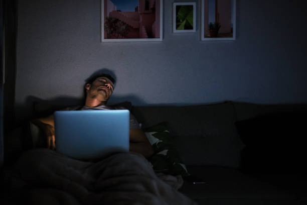 man sleeping with computer on - cair no sofá imagens e fotografias de stock