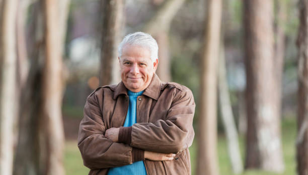 istock Senior man standing outdoors in park, arms crossed 1090450564