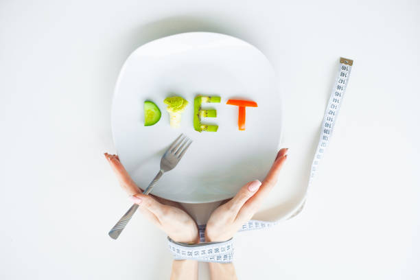 istock Diet or weight control concept. Centimeter tape and fork on a white background with a place for inserting text. concept of health, weight loss, diet, proper nutrition. Fitness and healthy food diet concept. 1090453002