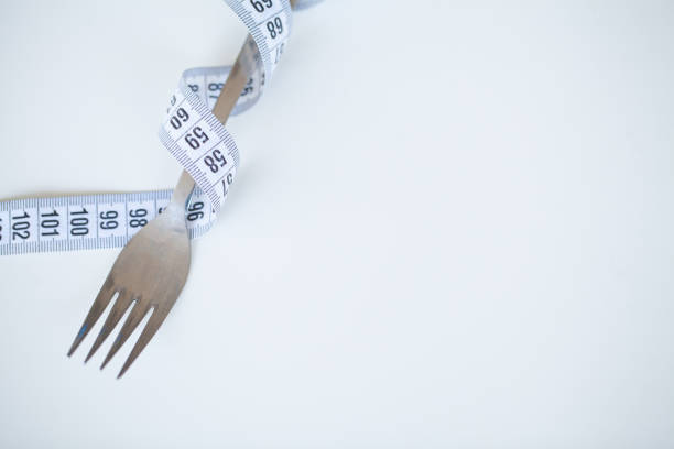 istock Diet or weight control concept. Centimeter tape and fork on a white background with a place for inserting text. concept of health, weight loss, diet, proper nutrition. Fitness and healthy food diet concept. 1090453100