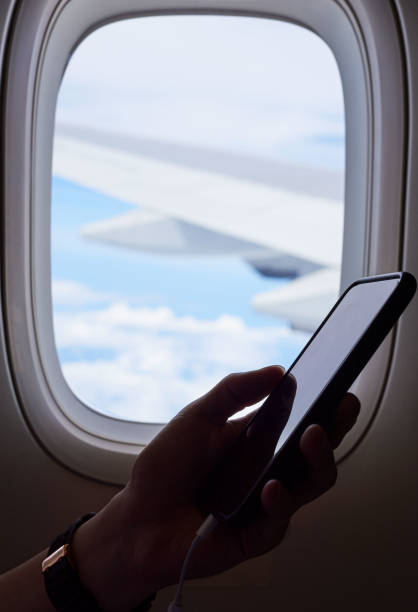istock A hand holding mobile phone inside airplane near the window 1090453304