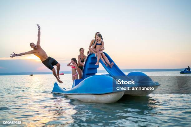 Happy Family Enjoying Summer Sunset On Lake With Pedal Boat Stock Photo - Download Image Now