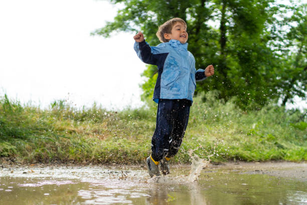 istock little boy jumping in rain water puddle 1090462880