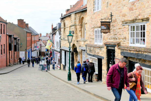 Lincoln, Lincolnshire, UK. May 01, 2016. Toursts and locals walking Steep hill passing the Norman built Jew's house and Jew's court at Lincoln in Lincolnshire, UK.