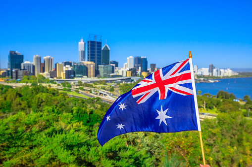 Australian flag waving aver Perth Water, a section of Swan River, and central business district of Perth from Kings park, the most popular visitor destination in WA. Blue sky. Perth skyline aerial