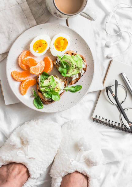 istock Breakfast in bed. Coffee, avocado sandwiches, boiled egg and tangerine on a light background, top view. Morning inspiration 1090471962