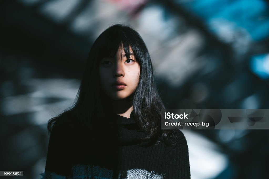 Portrait of young Asian woman A portrait of a young Asian woman while half of her face is lit by the sun and the other half is in the shadow. One Woman Only Stock Photo