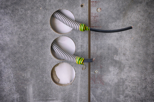 Plastic corrugated pipes with electric cable inside sticking out of wall for power sockets.