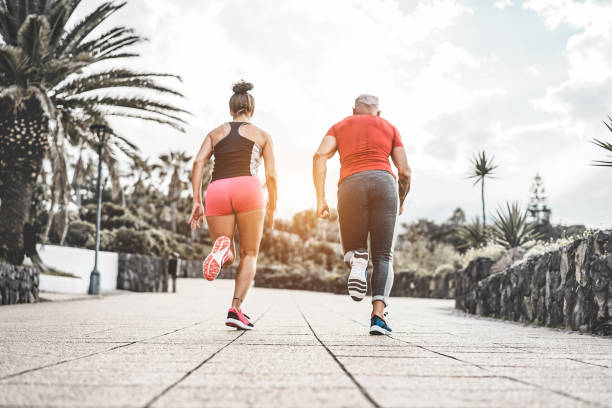 Couple of fitness friends running outside at sunset time - Sportive people training at evening sprinting outdoor - Jogging, healthy lifestyle and sport concept - Focus on feet shoes Couple of fitness friends running outside at sunset time - Sportive people training at evening sprinting outdoor - Jogging, healthy lifestyle and sport concept - Focus on feet shoes miami marathon stock pictures, royalty-free photos & images