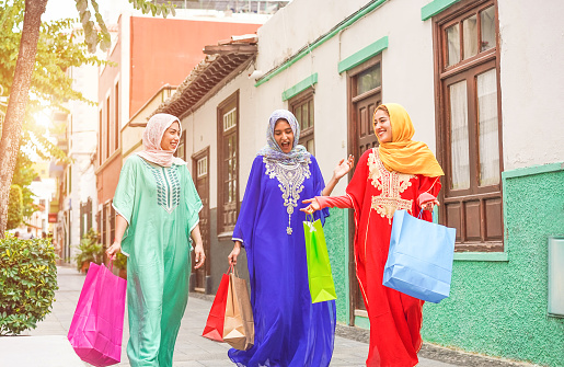 Happy arabian friends going back at home after shopping - Young islamic girls having fun together - Sale and friendship concept - Focus on faces