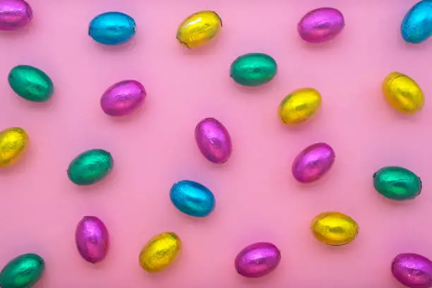 Photo of Easter eggs in colorful foil over pink, holiday background