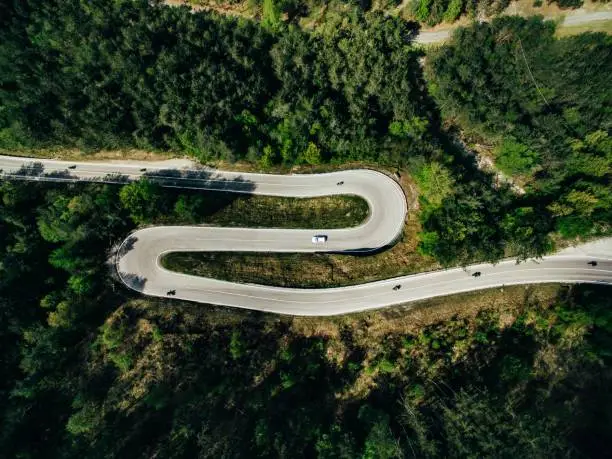 Photo of Aerial above view of a rural mountain landscape with a curvy road in Italy.
