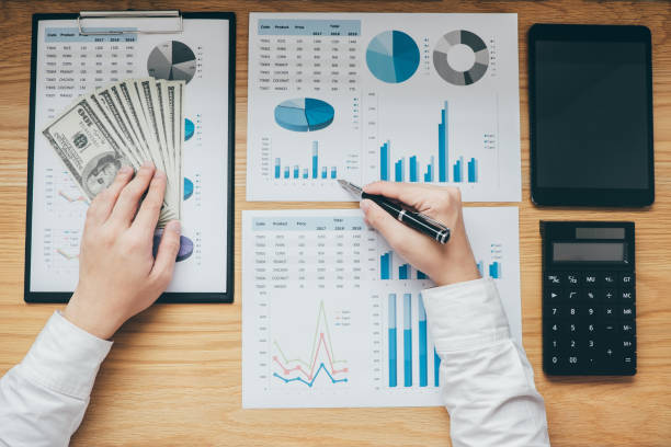 istock Businessman working on a graph document financial report and analysis calculation cost with calculator at office desk and other objects around, Top view workspace 1090495372