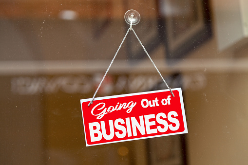 Red sign hanging at the glass door of a shop saying: 