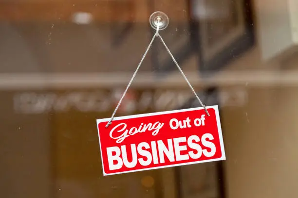 Red sign hanging at the glass door of a shop saying: "Going out of business".