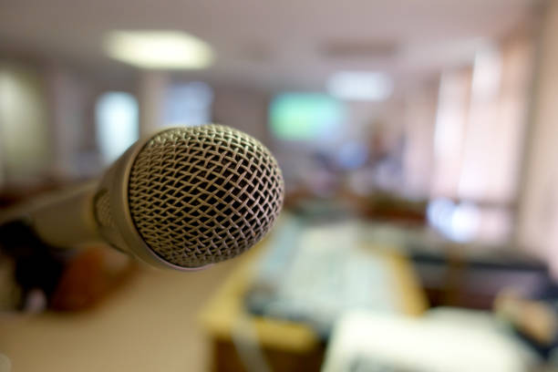 istock Vintage microphone over the Abstract blurred image of conference hall, study room or seminar room with attendee background, Small Business training concept, Public speaking 1090501784
