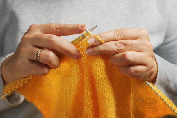 Woman hands with knitting needles and wool yarn. Needlework concept. Woman hands knitting with knitting needles and yellow soft wool yarn. Needlework concept. knitting needle photos stock pictures, royalty-free photos & images