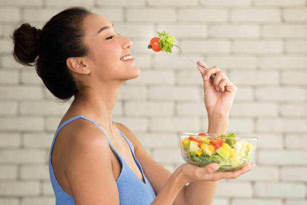 Asian woman in joyful postures with salad bowl on the side Asian woman in joyful postures with hand holding salad bowl WOMAN LOSING WEIGGHT stock pictures, royalty-free photos & images