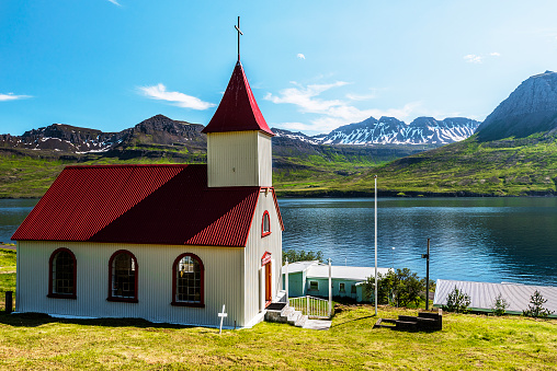 The church of Mjoifjordur village and the landscape of the fjord and mountain cost at the background. Austurland, Fjardabyggd, Eastern Iceland