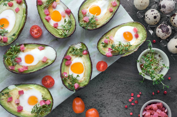 istock Keto diet dish: Avocado boats with ham cubes, quail eggs and cherry tomatoes on marble serving board 1090523454