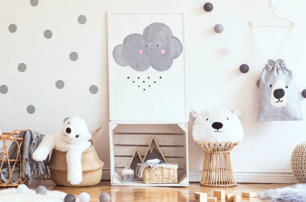 istock Scandinavian child room with mock up poster frame on the pattern wall, boxes, teddy bear and toys. Cute modern interior of playroom with white walls, wooden accessories and colorful toys. 1090539134