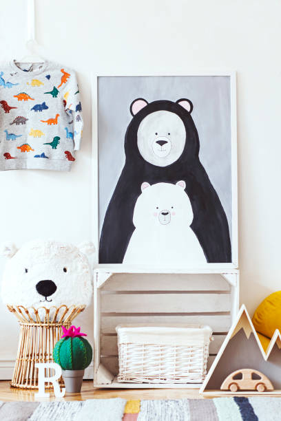 istock Scandinavian child room with mock up photo poster frame on the pattern wall, boxes, teddy bear and toys. Cute modern interior of playroom with white walls, wooden accessories and colorful toys. 1090539146