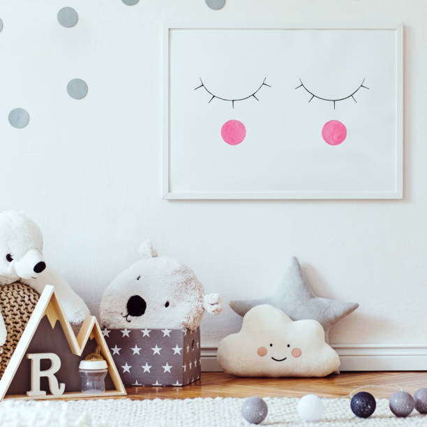 istock Stylish scandinavian child room with mock up photo poster frame on the pattern wall, boxes, teddy bear and toys.Cute modern interior of playroom with white walls, wooden accessories and colorful toys. 1090539546
