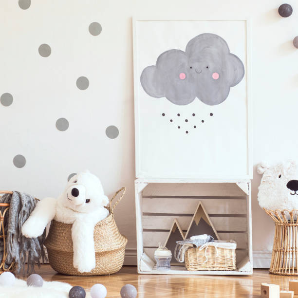 istock Scandinavian child room with mock up poster frame on the pattern wall, boxes, teddy bear and toys. Cute modern interior of playroom with white walls, wooden accessories and colorful toys. 1090539566
