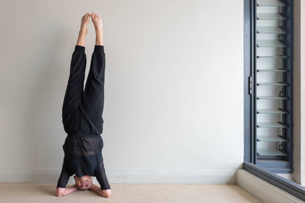 vielles femmes faisant headstand dans studio d’yoga - inversion yoga photos et images de collection