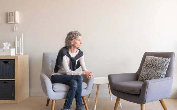 Photo of Middle aged woman seated alone with empty armchair