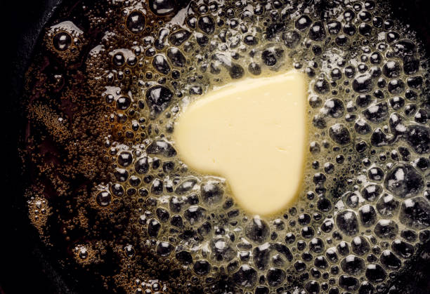 Fried butter, a piece of butter in the shape of hearts, fried on a black cast-iron pan. Fried butter, a piece of butter in the shape of hearts, fried on a black cast-iron pan. Impression about a healthy heart, anti cholesterol prophylaxis, healthy heart concept colloid stock pictures, royalty-free photos & images