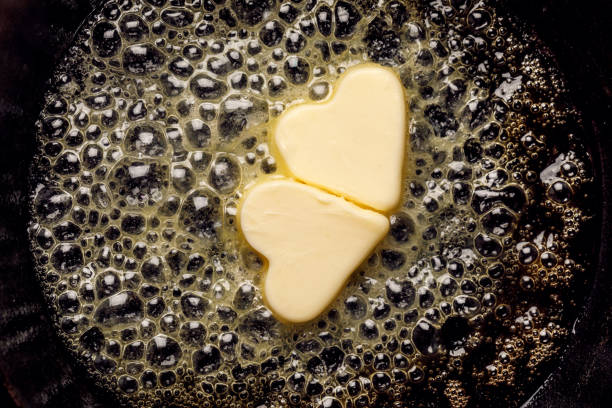 Fried butter, a piece of butter in the shape of hearts, fried on a black cast-iron pan. Fried butter, a piece of butter in the shape of hearts, fried on a black cast-iron pan. Impression about a healthy heart, anti cholesterol prophylaxis, healthy heart concept colloid stock pictures, royalty-free photos & images